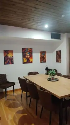 a table and chairs in a room with paintings on the wall at El mirador del Rosal in Ponferrada