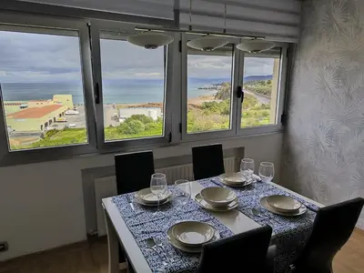a dining room with a table with chairs and windows at Castrelo 4A in Burela de Cabo