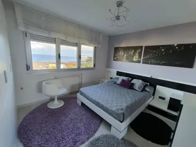 a bedroom with a bed and a chair and two windows at Castrelo 4A in Burela de Cabo