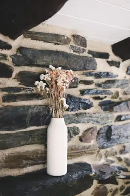 a white vase with flowers sitting on a stone wall at Casa Amencer in Francos