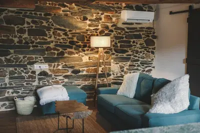 a living room with two blue couches and a stone wall at Casa Amencer in Francos
