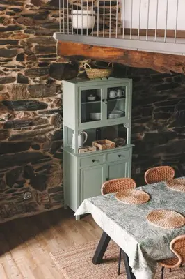 a table with a green cabinet in a room with a stone wall at Casa Amencer in Francos