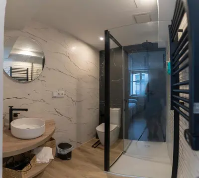 a bathroom with a toilet and a glass shower at NOARU Apartamentos Deluxe in Ares