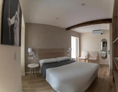 a bedroom with a bed and a table and chairs at NOARU Apartamentos Deluxe in Ares