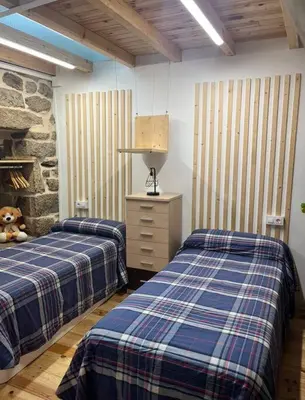 a bedroom with two beds and a stone wall at O Capricho in Requeixo