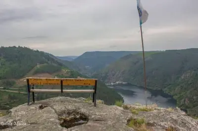 a bench sitting on top of a mountain overlooking a river at O Capricho in Requeixo