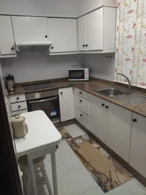 a kitchen with white cabinets and a sink and a table at Pontedeume cerca del mar y la naturaleza in Puentedeume