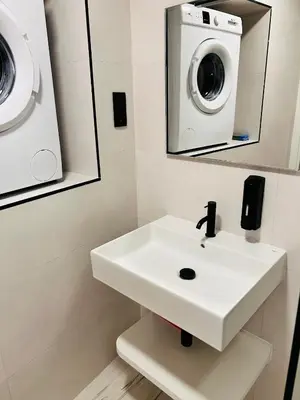 a bathroom with a sink and a washing machine at APARTAMENTOS NADA Ó NORTE Centro in Viveiro