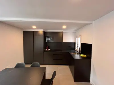 a kitchen with black cabinets and a table and chairs at APARTAMENTOS NADA Ó NORTE Centro in Viveiro