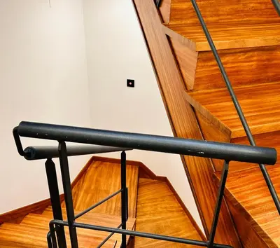 a black rail on a wooden staircase with wooden floors at APARTAMENTOS NADA Ó NORTE Centro in Viveiro