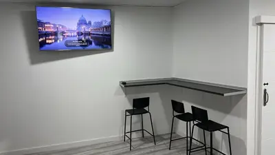 a room with three bar stools and a tv on a wall at O Albergue de Fene in Fene