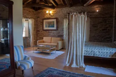 a bedroom with a bed and a couch and a chair at Pazo Santa María in Arzúa