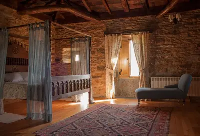 a bedroom with a bed and a chair and a window at Pazo Santa María in Arzúa