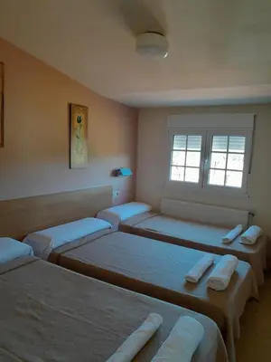 a room with four beds and a window at Restaurante y Hostal San Paio in Santiago de Compostela