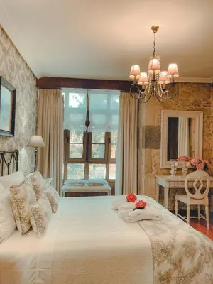a bedroom with a large white bed with a chandelier at Torre do Rio in Caldas de Reis