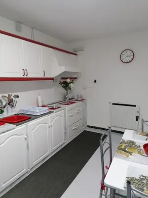 a kitchen with white cabinets and a table and a clock at VT Maria in Ribadeo