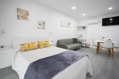 a white bedroom with a bed and a table and chairs at Huna Apartamentos in Padrón