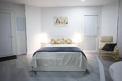 a white bedroom with a bed and a chair at Huna Apartamentos in Padrón