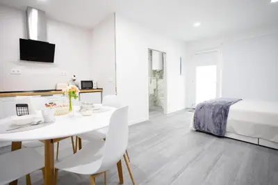 a white room with a bed and a white table and chairs at Huna Apartamentos in Padrón