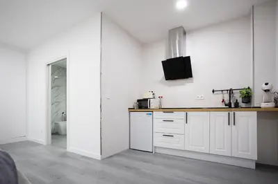 a kitchen with white cabinets and a sink at Huna Apartamentos in Padrón