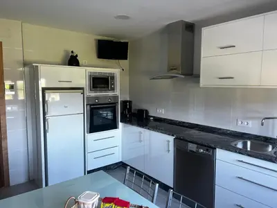 a kitchen with white cabinets and white appliances at APARTAMENTO FOZ Imr in Foz