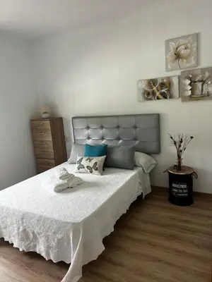 a bedroom with a bed with white sheets and blue pillows at APARTAMENTO FOZ Imr in Foz
