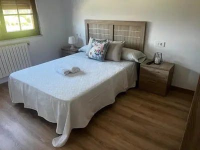 a bedroom with a large bed with a wooden headboard at APARTAMENTO FOZ Imr in Foz