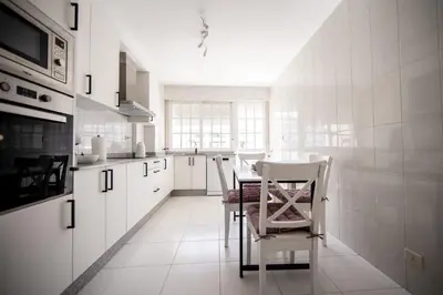 a kitchen with white cabinets and a table and chairs at Dulces Estancias in Lalín