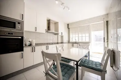 a kitchen with white cabinets and a table and chairs at Dulces Estancias in Lalín
