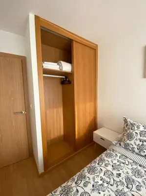 a small bedroom with a bed and a wooden closet at Apartamento a pie de playa La Pepa in Burela de Cabo