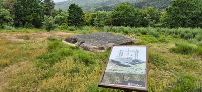 a sign in a field with a large rock at Casa Castrexa in Novoa