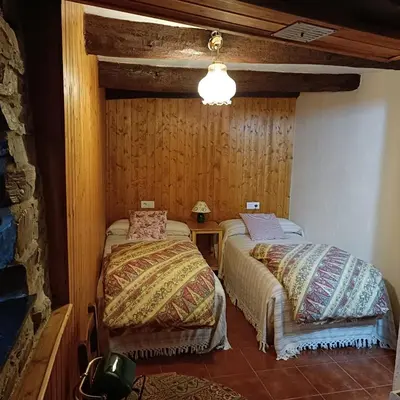 two beds in a room with wooden walls at Casa del agua in Espinoso de Compludo