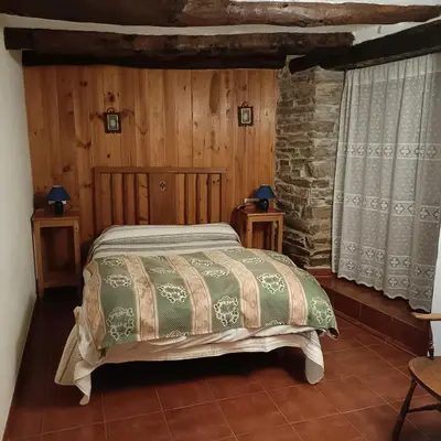a bedroom with a bed and a stone wall at Casa del agua in Espinoso de Compludo