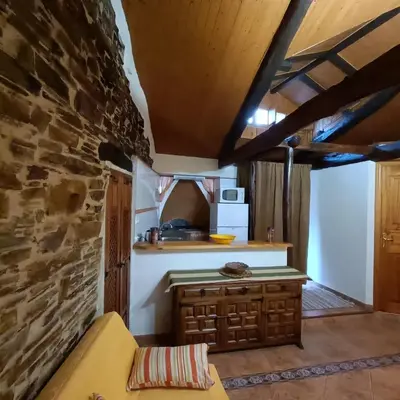 a kitchen with a table and a stone wall at Casa del agua in Espinoso de Compludo