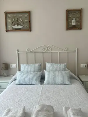a bed with two pillows and a clock on the wall at Cuatro Calles Picarolas in Ribadeo