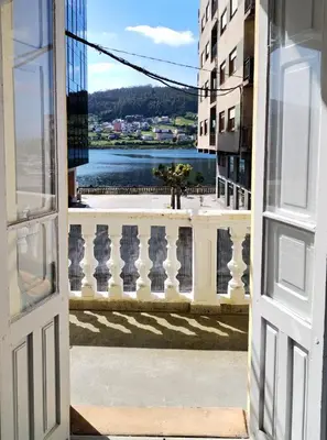 an open door to a balcony with a view of the water at Yellow House in Viveiro