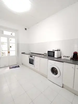a white kitchen with a washing machine and a microwave at Yellow House in Viveiro