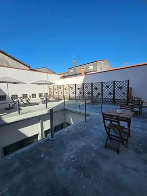 a patio with tables and umbrellas on a building at Pensión Casa Cruceiro in Arzúa