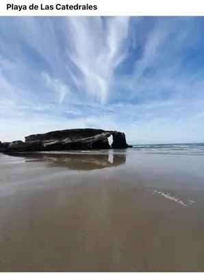 a large rock on a beach with the ocean at O xualtar Océano 2 in Villadaíde