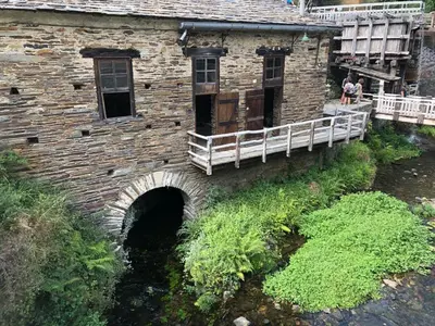 an old stone building with a bridge over a river at O xualtar Océano 2 in Villadaíde
