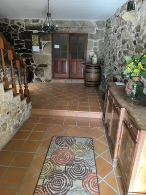 a room with a stone wall and a tile floor with a door at Casa o Pontillón in Rabiño