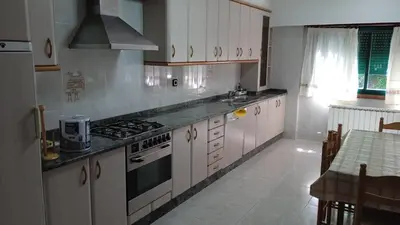 a kitchen with white cabinets and a stove top oven at Casa o Pontillón in Rabiño