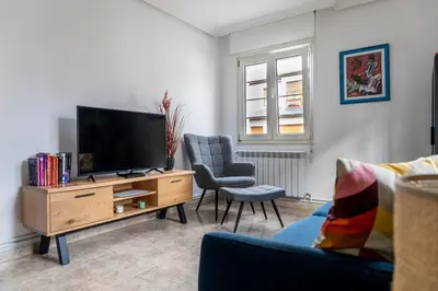 a living room with a flat screen tv and two chairs at Piso Turístico Las Nisas I in Puerto de Vega