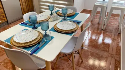 a table with white chairs and a white table with a cake on it at Apartamento Ainaran Confortable apartamento en el centro de Orense in Ourense