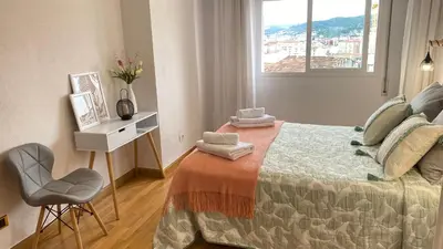 a bedroom with a bed with a chair and a window at Apartamento Ainaran Confortable apartamento en el centro de Orense in Ourense