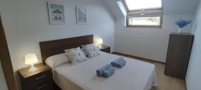 a bedroom with a bed with two blue towels on it at Mariña in Viveiro