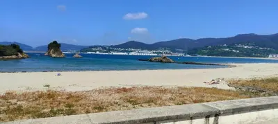 a beach with some people laying on the sand at Mariña in Viveiro