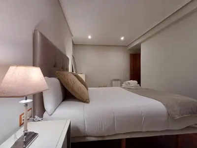 a bedroom with a white bed and a couch at Bedoya - Amplio y moderno piso en pleno centro de Ourense in Ourense
