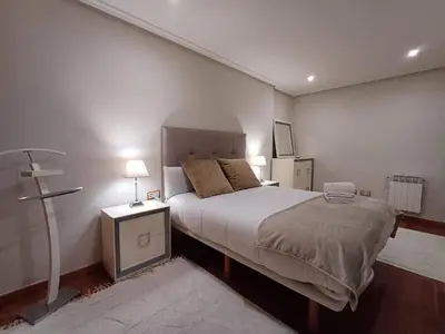 a bedroom with a bed and two lamps and a cross at Bedoya - Amplio y moderno piso en pleno centro de Ourense in Ourense
