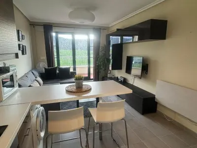 a kitchen and living room with a table and chairs at Costa SPA Ático de lujo - Playa de las Catedrales in San Miguel de Reinante